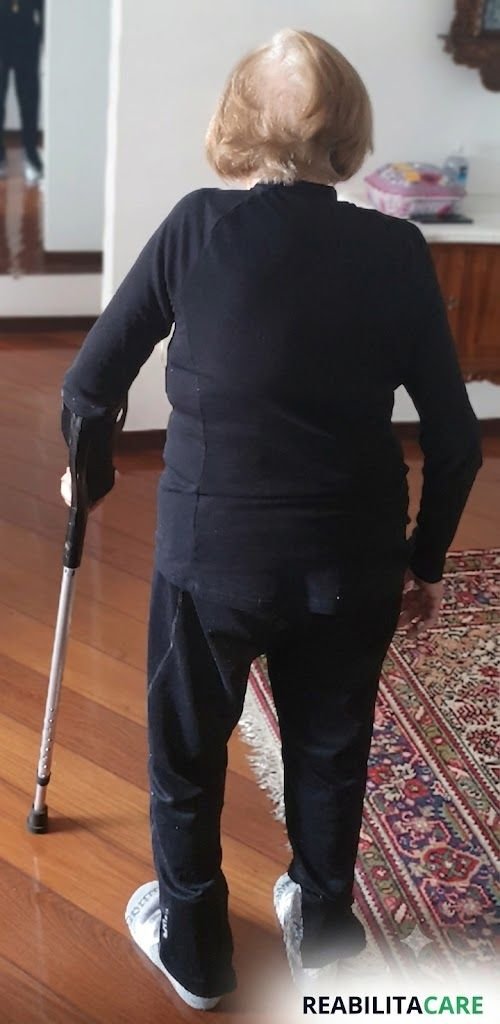 Paciente idosa treinando marcha em casa com apoio de muleta